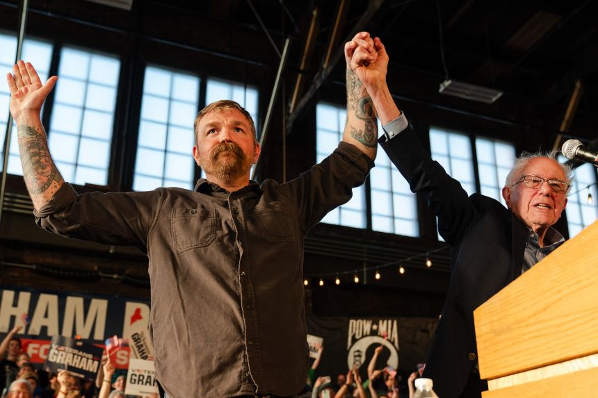 Graham Platner stands with Sen. Bernie Sanders, during a "Fighting Oligarchy" event in Portland, Maine on May 25.