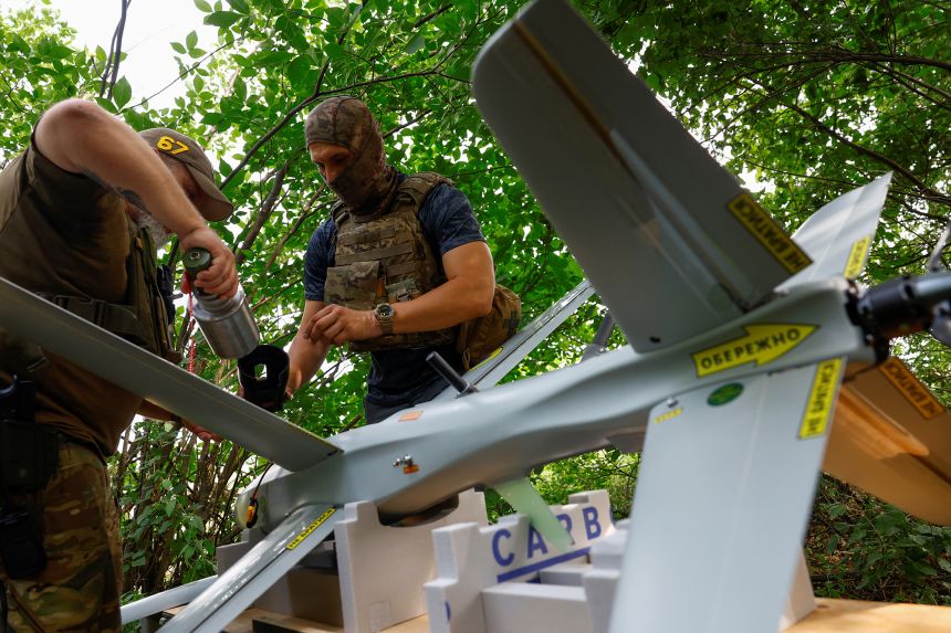 Service members of the 422nd Unmanned Systems Regiment prepare a strike drone for a flight in an undisclosed location in southern Ukraine.