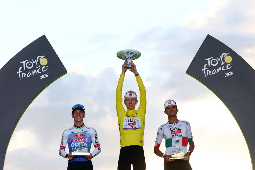 Pogacar celebrates on the podium while wearing the yellow jersey after winning the Tour de France, alongside UAE Team Emirates XRG's Isaac Del Toro and Red Bull - BORA - hansgrohe's Remco Evenepoel RE