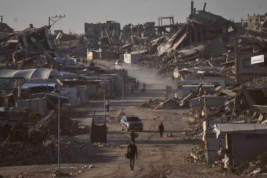 Palestinians walk along a road surrounded by buildings destroyed in Israeli military strikes during the Israel-Hamas war, in Jabaliya, Gaza Strip, on July 2, 2026.