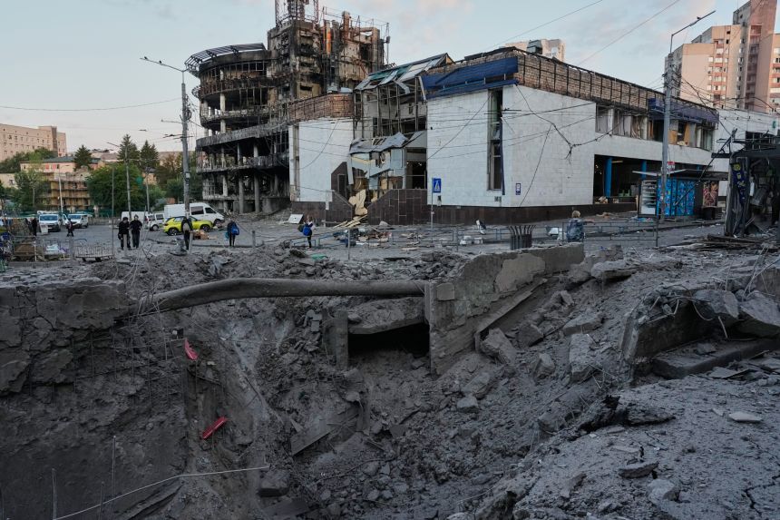 ap26200132412200 Debris surrounds a missile crater in the foreground of a building following Russia's missile attack in Kyiv on Sunday.