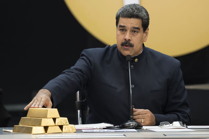 Nicolas Maduro, Venezuela's former president, touches a stack of 12 Kilogram gold ingots during a news conference on the country's cryptocurrency in Caracas on March 22, 2018.