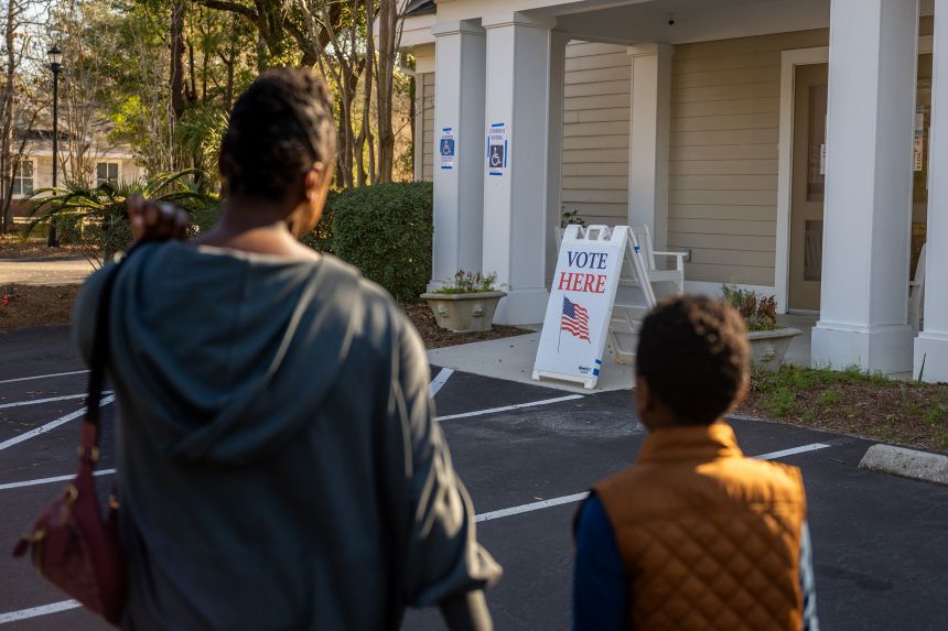 A woman walks with her son as she prepares to cast their ballot in the Democratic presidential primary at the Eastbridge Presbyterian Church in Mount Pleasant, South Carolina, on February 3, 2024.