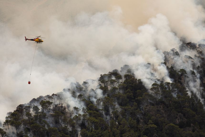 gettyimages-2223493909 A helicopter carries water over a fire near Xerta, Spain, in the summer of 2025 — a town 15 miles away from Tivissa, where the "firefighter donkeys" roam.