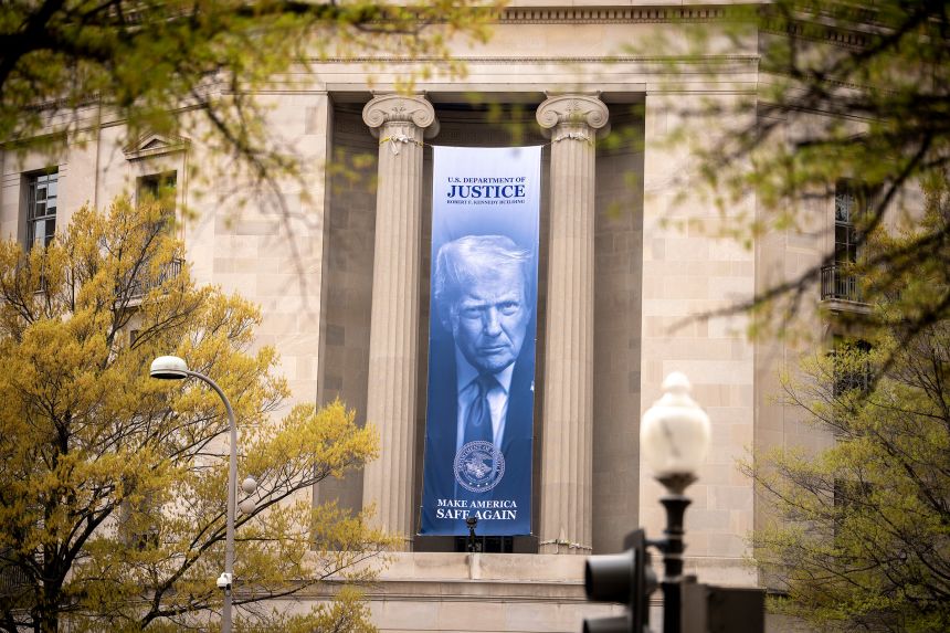 An image of President Donald Trump hangs from the Justice Department in Washington, DC, on April 3, 2026.