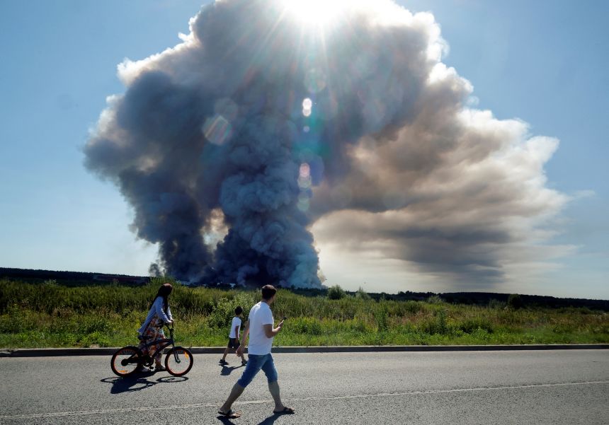 Local residents walk past the smoke of a fire at the Russian e-commerce firm Wildberries' logistics complexes in the town of Elektrostal outside Moscow on July 18.
