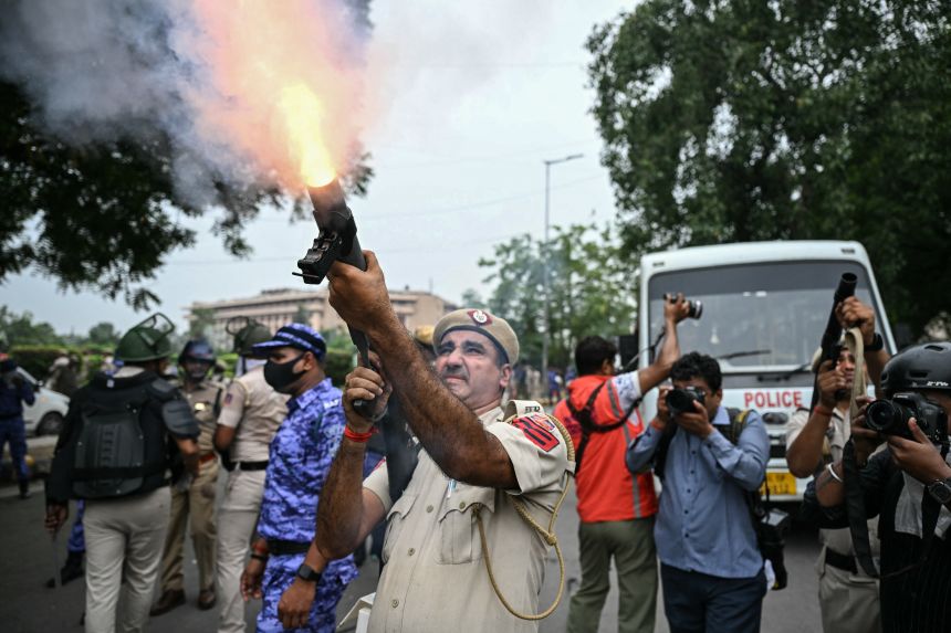 A police personnel fires tear gas shells to disperse activists and supporters of the Cockroach Janta Party (CJP) during a protest demanding the resignation of India's Education Minister Dharmendra Pradhan over alleged NEET examination irregularities in New Delhi on July 20, 2026.