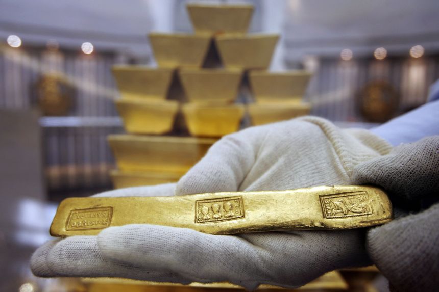 A Roman gold bar from the 4th century is handled by curator John Keyworth in front of replica modern bars at the Bank of England museum on May 12, 2006.
